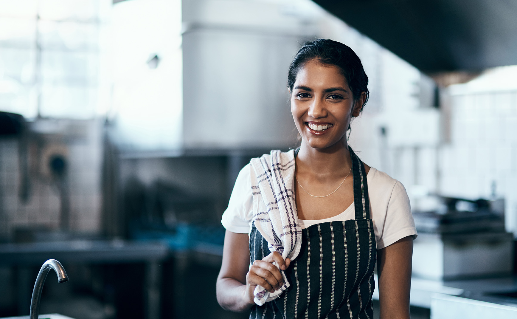 Portrait of a confident young woman standing in the kitchen of her cafe